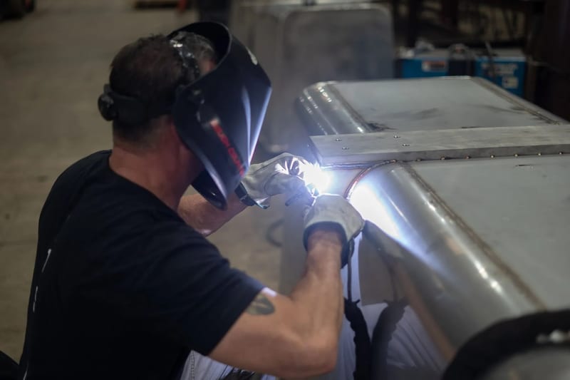 Welder working along the edge of a stainless-steel trough