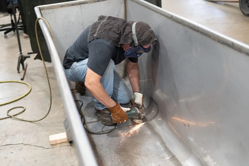 Technician finishing the inside of a stainless-steel trough