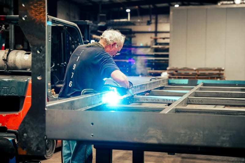 Welding a large rectangular steel assembly on the shop floor