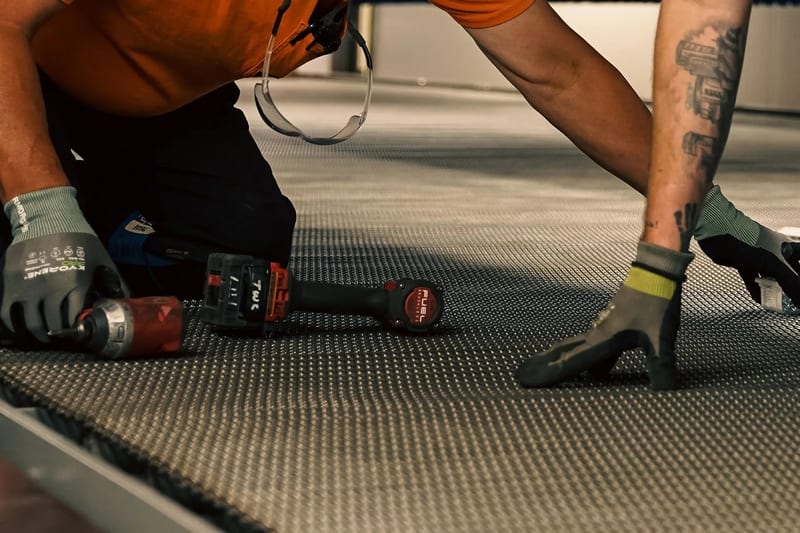 Technician working on a conveyor belt with a handheld power tool