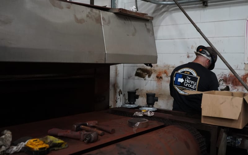 A THG field technician working at an open oven on a service visit