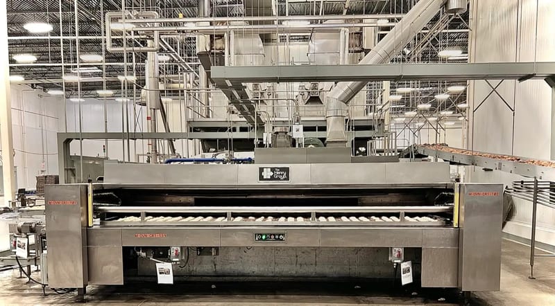 Commissioned Henry Group oven, nameplate centered, with dough pieces entering on the conveyor belt