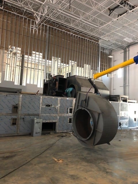 Lifting equipment positioning a cylindrical assembly beside oven modules