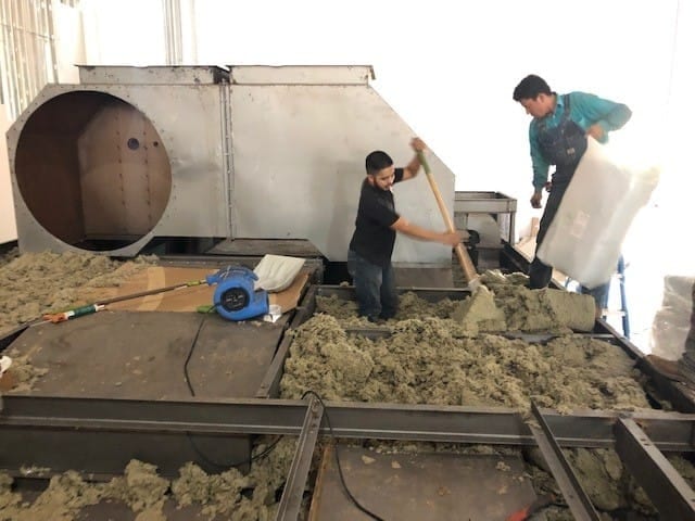 Two technicians working on the upper section of an oven module