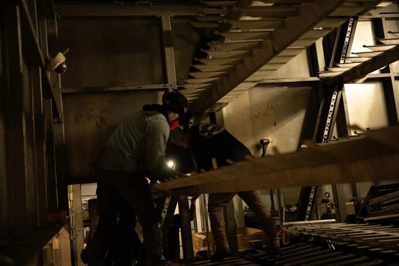 Two technicians working between internal oven trays and supports