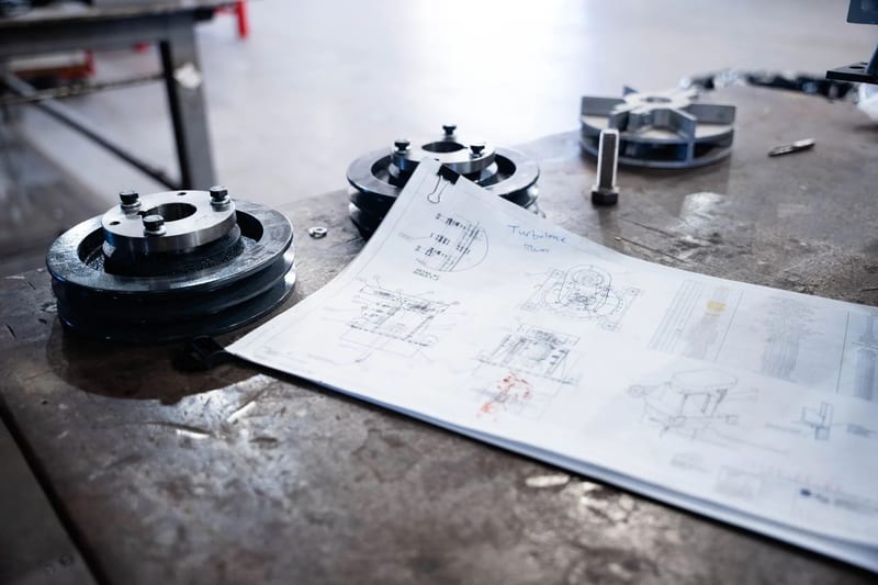 Machined components laid out beside a technical drawing