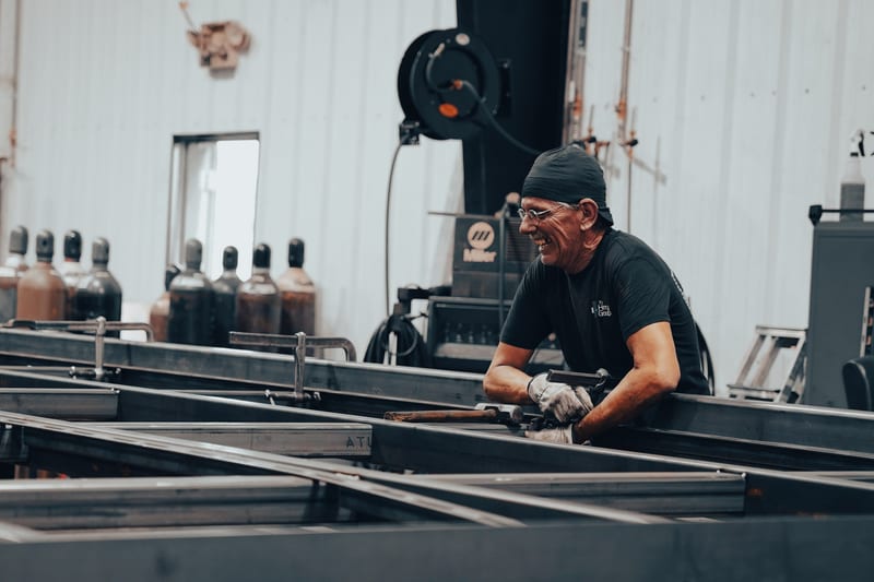 THG welder working on long steel frames in the fabrication shop