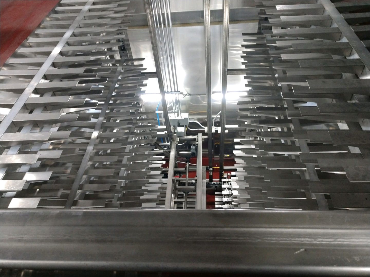Rows of metal product carriers inside a traveling-tray proofer