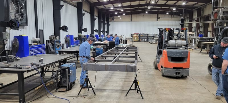 Welders building a steel bridge frame on stands in the shop